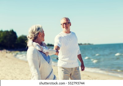 family, age, travel, tourism and people concept - happy senior couple holding hands on summer beach - Powered by Shutterstock