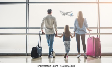 Family in airport. Attractive young woman, handsome man and their cute little daughter are ready for traveling! Happy family concept.