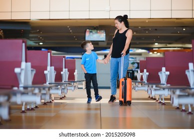 Family At Airport Before Flight. Mother And Son Waiting To Board At Departure Gate Of Modern International Terminal. Traveling And Flying With Children. Mom With Baby And Toddler Boarding Airplane.