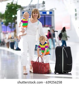 Family At Airport Before Flight. Mother And Kids Waiting To Board At Departure Gate Of Modern International Terminal. Traveling And Flying With Children. Mom With Baby And Toddler Boarding Airplane.