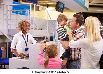 Family At Airport Check In Desk Leaving On Vacation