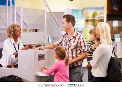 Family At Airport Check In Desk Leaving On Vacation