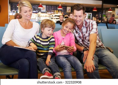 Family In Airport Departure Lounge Waiting To Go On Vacation