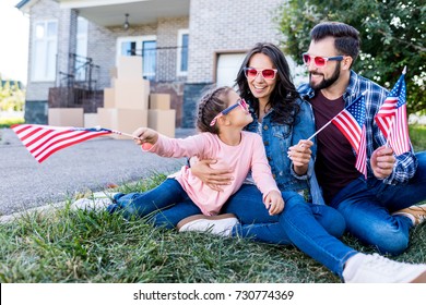 family with american flags and sunglasses sitting in garden of new house - Powered by Shutterstock