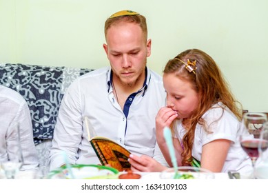 Family Around The Table For The Traditional Passover Dinner Reading The Haggadah. Jewish Family At The Feast Of Passover. Selective Focus On Man.