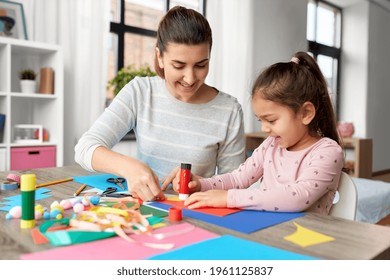 family, art and craft concept - mother spending time with her little daughter with glue making applique of color paper at home - Powered by Shutterstock