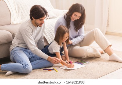 Family Art. Proud Parents Looking At Their Drawing Little Daughter At Home, Enjoying Spending Time Together