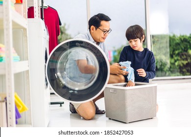 Family Asian Father And Kid Little Boy Son Having Fun Doing Household Chores Doing Laundry Dirty Clothes Into The Washing Machine Together In Laundry Room At Home