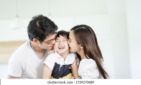 Family Asian Happy Kiss Little Boy At Home, Young Parent And Children Enjoy Love Hug Sitting On Couch Or Sofa Together