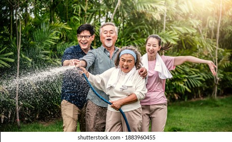 Family Asian Happy Using A Hose To Spray Water On The Plants