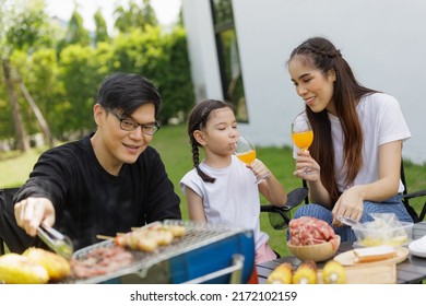 Family Asian Having Barbecue Party In Garden At Home. Grilled Corn. Smiling Parents Roast Beef With Daughter In Camping