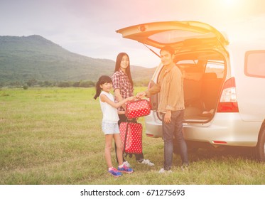 Family : Asian Family Travel In Car .transport, Leisure, Travel, Road Trip And People Concept - Happy Family Packing Things Into Car At Home Parking