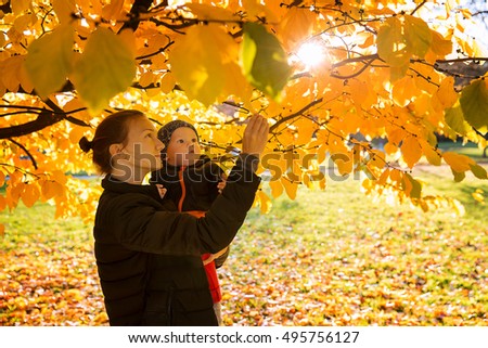 Family in the autumn park. Mom playing with son child in the autumn nature. Mom and her little baby child happy together.