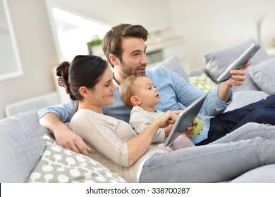 Family with baby in sofa watching tv 