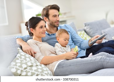 Family With Baby In Sofa Watching Tv 