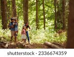 Family With Backpacks Hiking Or Walking Through Woodland Countryside