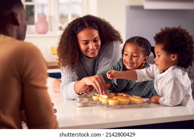 Family Baking Cupcakes Sitting Around Kitchen Counter At Home