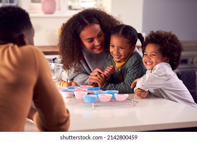 Family Baking Cupcakes Sitting Around Kitchen Counter At Home