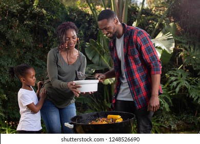 A family barbecuing food outside - Shutterstock ID 1248526690