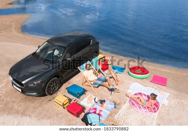 Family with beach accessories and car near river.\
Summer trip