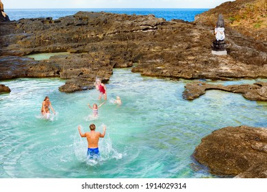 Family beach holiday lifestyle. Happy people have fun in natural sea pool at Angel’s Billabong on Pasih Uug. Best travel destinations on Bali island. Popular place during Nusa Penida day tour.