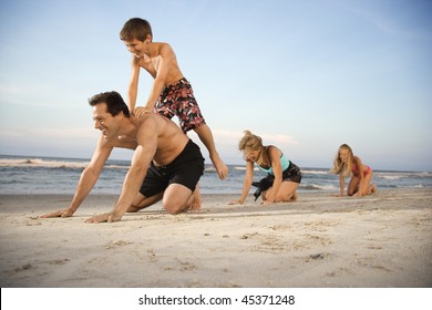 Family At The Beach Playing Leap Frog. Horizontal Shot.