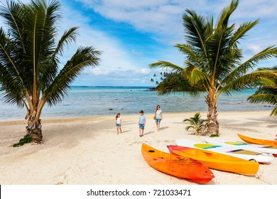 Family  At Beautiful Tropical Beach With Palm Trees, White Sand, Turquoise Ocean Water And Blue Sky At Cook Islands, South Pacific