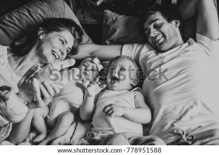 Relaxed mother and sons playing over the bed