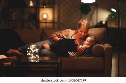 Family Before Going To Bed Mother Reads To Her Child Son Book Near A Lamp In The Evening
