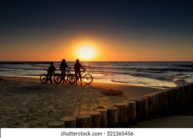 Family With Bicycles On The Baltic Sea At Sunset