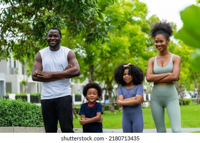 A Family Of Black Americans And Their Son And Daughter In Sportswear Line Up To Take Pictures, Smiling Cheerfully At The Camera In Public Park