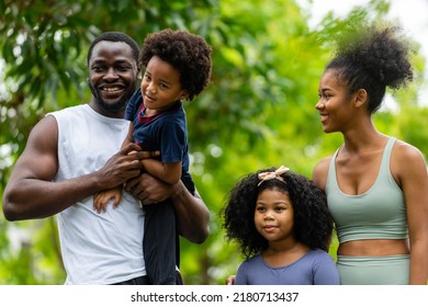 A Family Of Black Americans And Their Son And Daughter In Sportswear Line Up To Take Pictures, Smiling Cheerfully At The Camera In Public Park