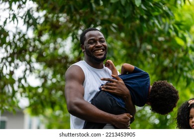 A Family Of Black Americans And Their Son And Daughter In Sportswear Line Up To Take Pictures, Smiling Cheerfully At The Camera In Public Park