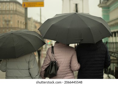 Family With Black Umbrellas. People Rain. Parents With Their Daughter Walk Around The City. Bad Weather On The Street.