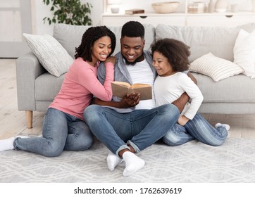 Family Bonding. Caring Black Man Reading Book To His Daughter And Wife, Enjoying Spending Time Together At Home