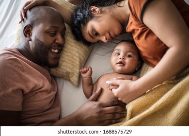 Family bonding time. African American parents with daughter on bed.