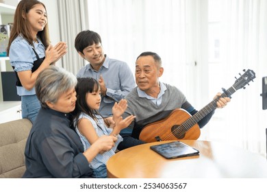 Family bonding time with multiple generations, grandparents with children, asian family gathering at home, grandpa playing guitar celebrating music together, relationships and joyful family moments - Powered by Shutterstock