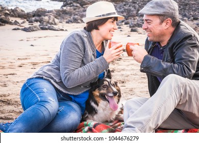 Family With A Border Collie Dog Doing Pic Nic Activity On The Beach In Vacation, Summer Lifestyle With Friends Concept. Old Style And Vintage Filter. Tea Break Time