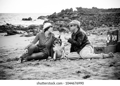 Family With A Border Collie Dog Doing Pic Nic Activity On The Beach In Vacation, Summer Lifestyle With Friends Concept. Old Style And Vintage Filter