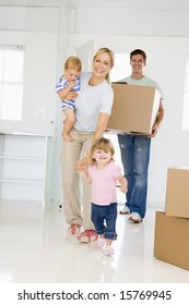 Family With Box Moving Into New Home Smiling