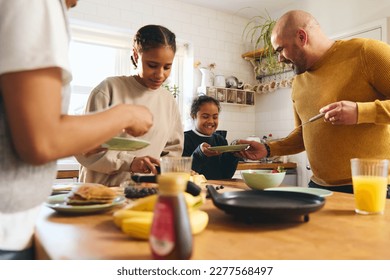 Family and boy with Down syndrome serving pancakes for breakfast - Powered by Shutterstock