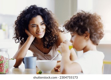 Family, breakfast and kid with mother in a home with happiness and orange juice with care. Mom, food and young child together with parent love and support with healthy drink and youth with a smile - Powered by Shutterstock