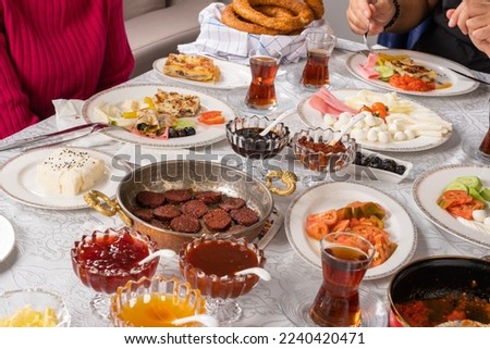 Family breakfast, morning routine of happy family breakfast. Traditional yummy modern Turkish cuisine. Simit, bagel, sucuk, sausage, cheese, tea in glass, tomatoes, jam, olive. 
