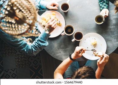Family breakfast at the oval table by the window. Father and two sons eating potatoes and drinking coffee from white ceramic mugs. Top view through a crystal chandelier. Weekend Family Customs Concept - Shutterstock ID 1564679440