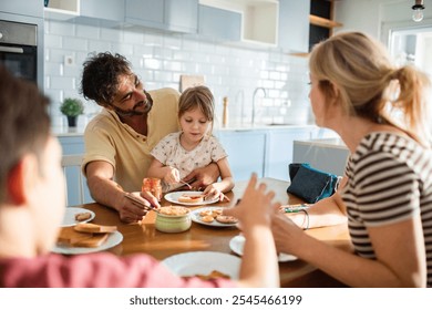 Family breakfast time with parents and child spreading jam on toast - Powered by Shutterstock