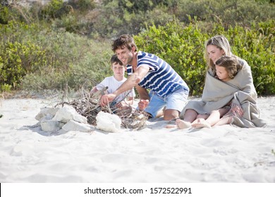 Family Building Campfire On Beach