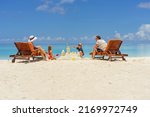 family building a sandcastle at the beach in summer - vacation time