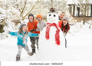 Family Building Snowman In Garden