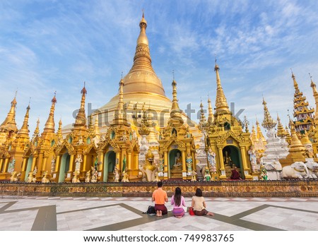 family burmese people  praying respects at Shwedagon big golden pagoda most sacred Buddhist pagoda in rangoon, Myanmar(Burma) on blue sky background