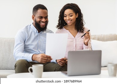 Family Business And Accounting. Cheerful Black Couple Holding Paper, Checking Household Expenses, Reading Documentation Or Receipt From Bank, Sorting Bills Or Planning Budget, Sitting On Couch